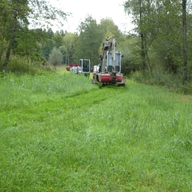 Der Bagger fährt über die Wiese zur Baustelle