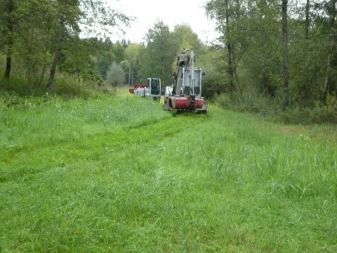Der Bagger fährt über die Wiese zur Baustelle