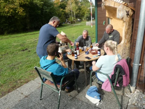 Helfer sitzen in der Sonne an einem Tisch vor der Hütte