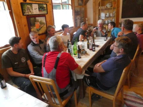 Die Runde sitzt in der Stube der Hütte an einem langen Tisch beisammen