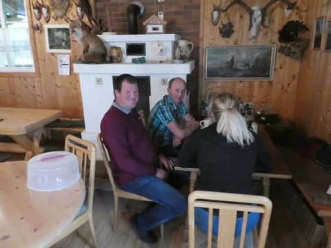 Drei Gäste unterhalten sich am Tisch in der Hüttenstube
